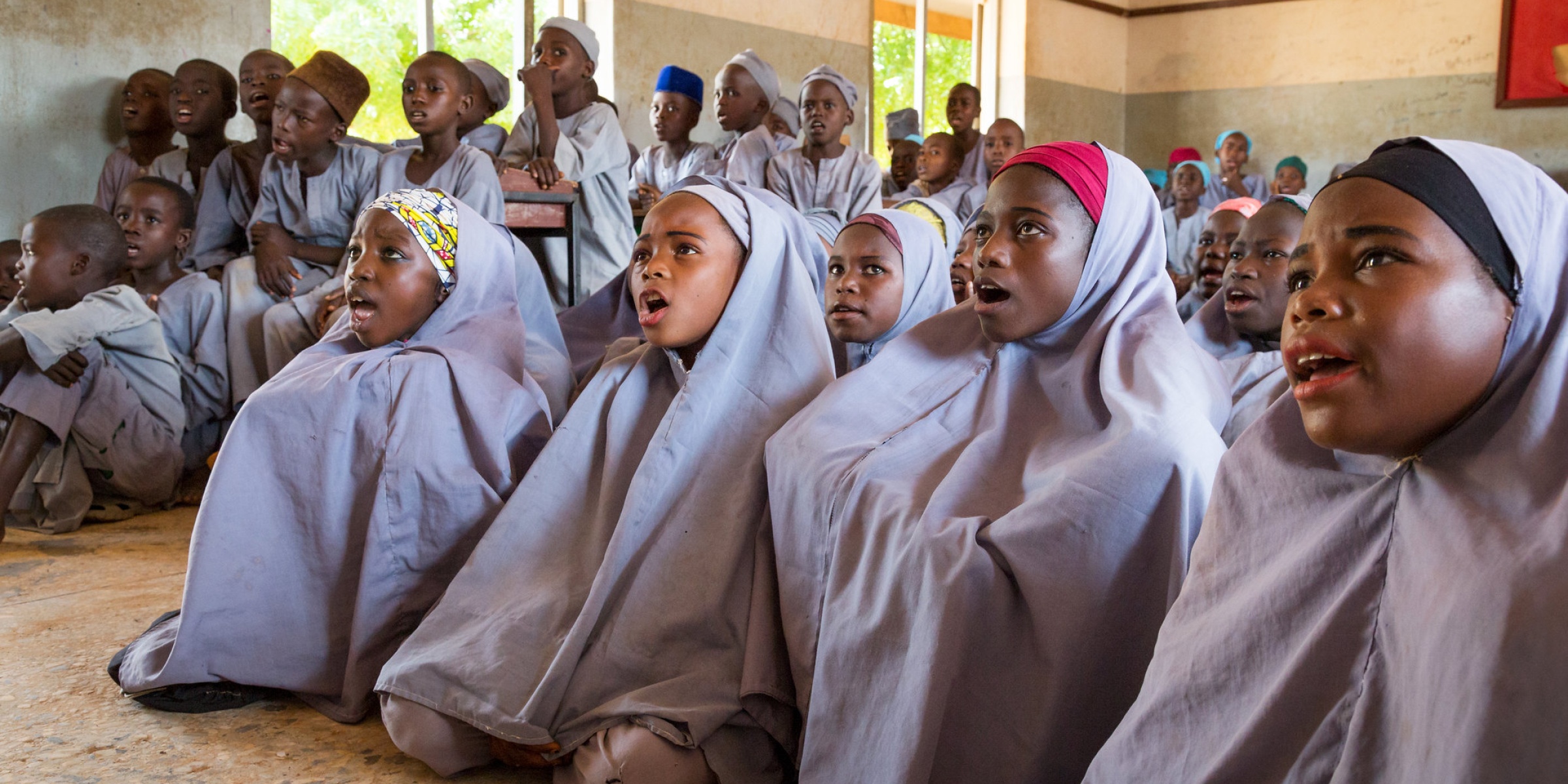 Sumayya Ado, 13 (second from right), and other girls sit on the floor at Janbulo Islamiyya Primary School, Roni, Jigawa State, Nigeria. Asked if she could change one thing about the school, she says, “I would add more classrooms. Our classes are too congested.” Credit: GPE/Kelley Lynch